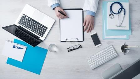 Overhead view of doctor writing on a clipboard