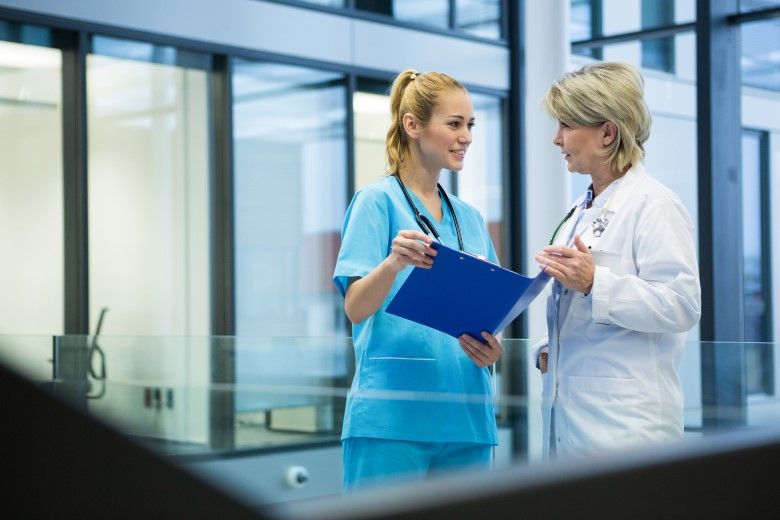 A nurse practitioner stands with another nurse in a medical facility.